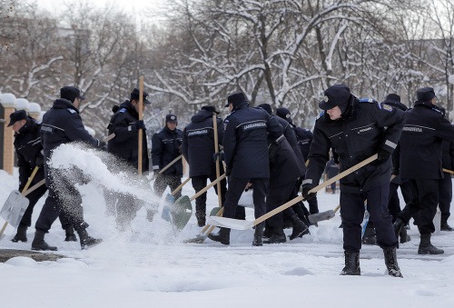 Bukurešť je v zajatí arktickej zimy, na snímke rumunskí policajti odhrabávajú sneh.