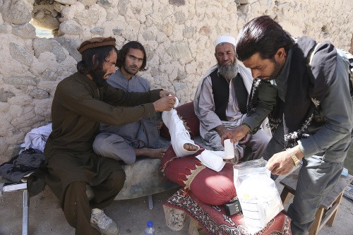 Afganskí policajti ošetrujú zraneného kolegu počas operácie USA proti militantom Daeš v Afganistane.