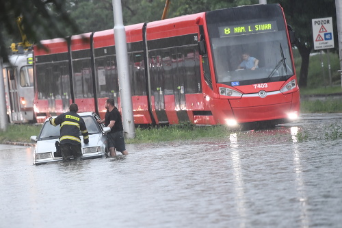 Na snímke hasič pomáha vodičovi na zaplavenej Ružinovskej ulici pod mimoúrovňovou križovatkou s Bajkalskou ulicou v Bratislave po silnej búrke.
