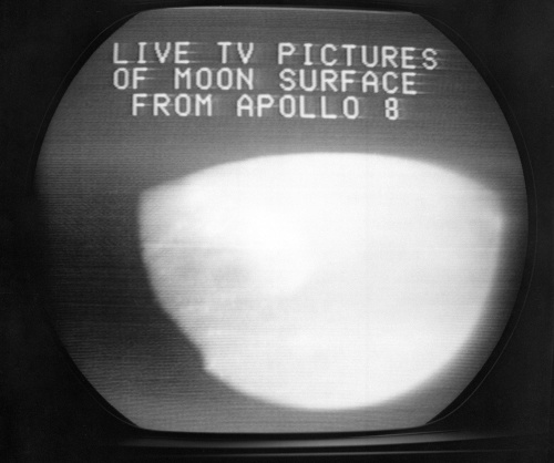 Fototografia zobrazuje televíznu obrazovku s pohľadom na mesiac vysielaný astronautmi Apollo 8