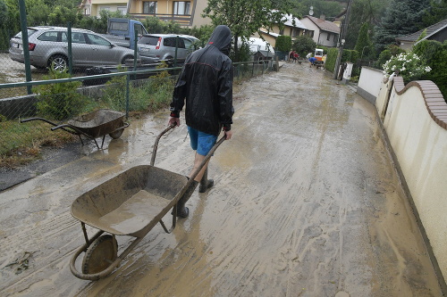 Na snímke odpratávanie vody a bahna zo zaplavenej ulice v obci Ratnovce (Trnavský kraj).