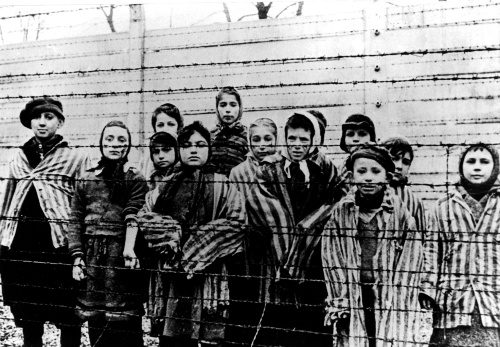 Na archívnej snímke z januára 1945 deti stoja za ostnatým drôtom v nacistickom koncentračnom  tábore v poľskom Osvienčime tesne po tom, ako tábor oslobodili sovietske jednotky, FOTO: TASR/AP