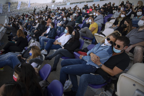 Diváci s rúškami počas koncertu izraelského speváka Ivriho Lidera na futbalovom štadióne v Tel Avive