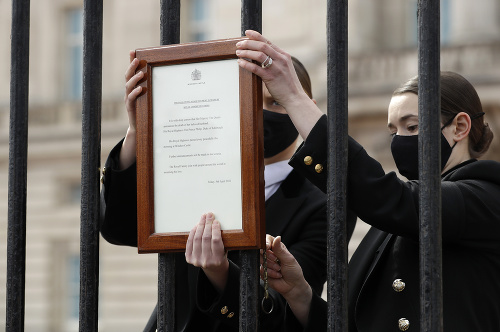 Členovia personálu vešajú oznámenie o úmrtí britského princa Philipa na bránu Buckinghamského paláca 9. apríla 2021 v Londýne.