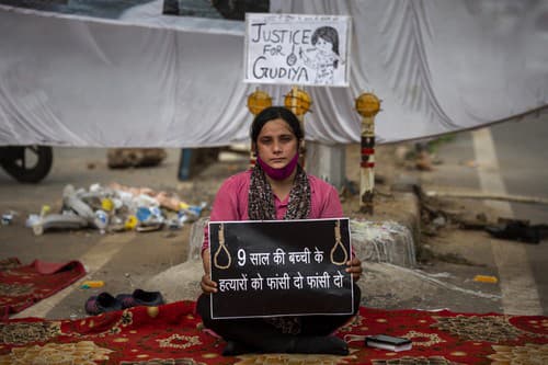 Sociálna aktivistka, drží transparent s nápisom „Obeste vrahov 9-ročného dieťaťa“.