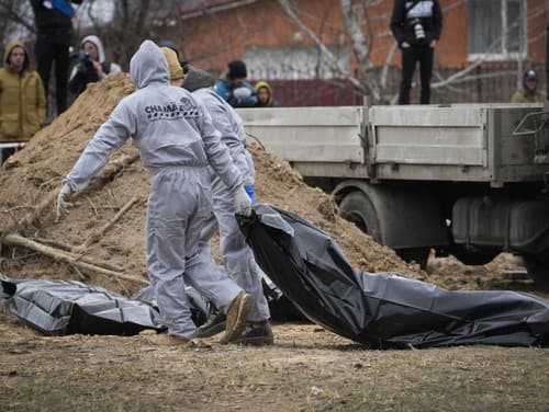 Muži v ochranných výstrojoch exhumujú telá civilistov zabitých počas ruskej okupácie v Buči