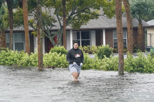 Wilfred Rosario kráča vo vode na zaplavenej ulici pri obytnom komplexe, kde sa chystá skontrolovať svojich príbuzných v meste Orlando na Floride.