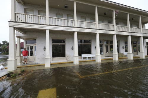 Bert Guy, spolumajiteľ historického hotela Riverview Hotel sa pozerá na stúpajúcu hladinu vody na zaplavenej ulici v centre mesta St. Mary's, v americkom štáte Georgia.