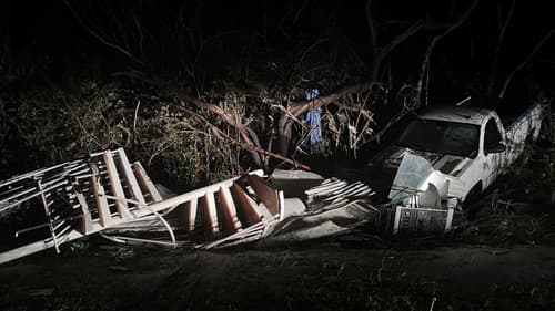 Zničené špirálovité schodisko leží v krove pri bielom pickupe na ostrove Sanibel, Florida.