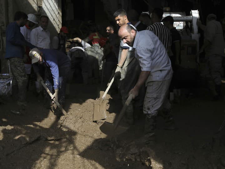 Záchranári a miestni obyvatelia odstraňujú bahno po prívalových povodniach v dedine ležiacej severozápadne od metropoly Teherán.