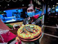 Zamestnankyňa ukazuje pizzu s