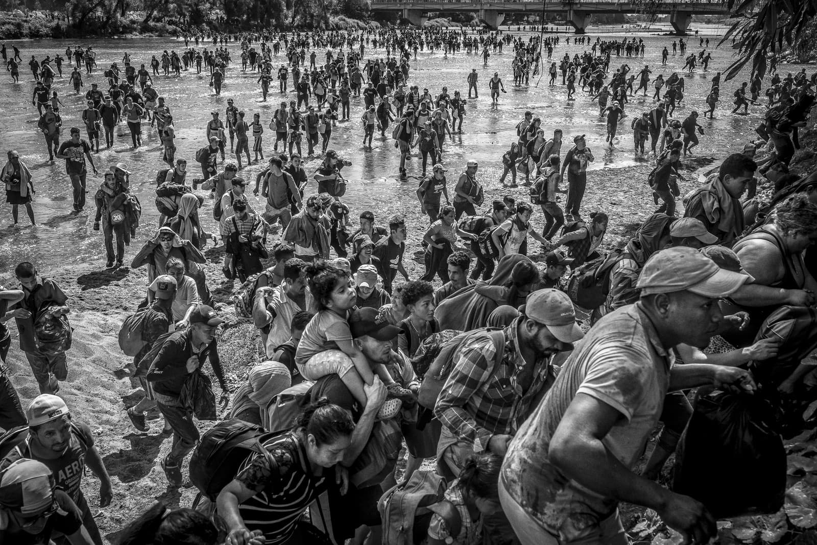 Ever Sosa (v strede) nesie na pleciach svoju dcéru, keď spolu prekračujú rieku Suchiate z Guatemaly do Mexika a pripájajú sa ku karaváne 3000 migrantov a žiadateľov o azyl, ktorí sa snažia dostať do Spojených štátov. V roku 2019 Mexiko podobnej karaváne udelilo humanitárne víza, do roku 2020 sa ale politika zmenila a požadovala rozpustenie akýchkoľvek karaván. Tisíce ľudí preto boli prinútené dostať sa do Mexika prekročením rieky Suchiate namiesto použitia Medzinárodného mosta Dr. Rodolfa Roblesa. Ciudad Hidalgo, Mexiko, 20. januára 2023.