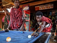 Mladý muž z africkej černošskej etnickej skupiny Masajov hrá biliard v bare pri ceste neďaleko Národného parku Mikumi v Tanzánii