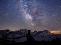 Muž sleduje Mliečnu dráhu na oblohe pred východom slnka v Ormont-Dessus vo švajčiarskych Alpách neďaleko Sionu.