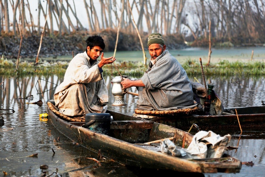 Kašmírsky rybár drží v ruke tradičný čajník počas zaslúženej prestávky.