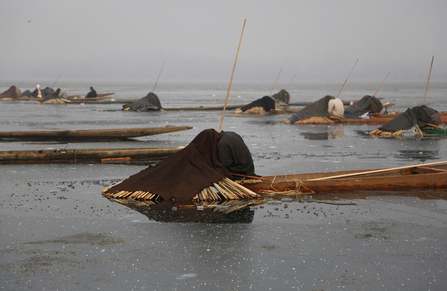 Kašmírski rybári čakajú schovaní pod prikrývkami na lodiach počas lovu rýb na čiastočne zamrznutom jazere Anchar na okraji Šrínagaru.
