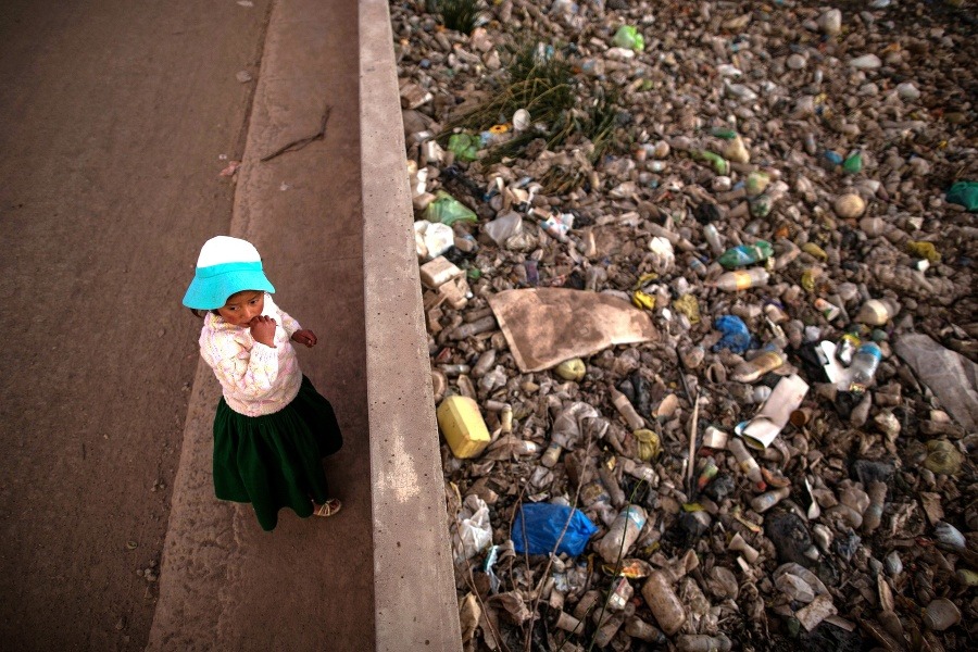 Dievča stojí pred znečisteným brehom rieky Torococha vedľa komunálnej čističky odpadových vôd, ktorá vyúsťuje do jazera Titicaca.