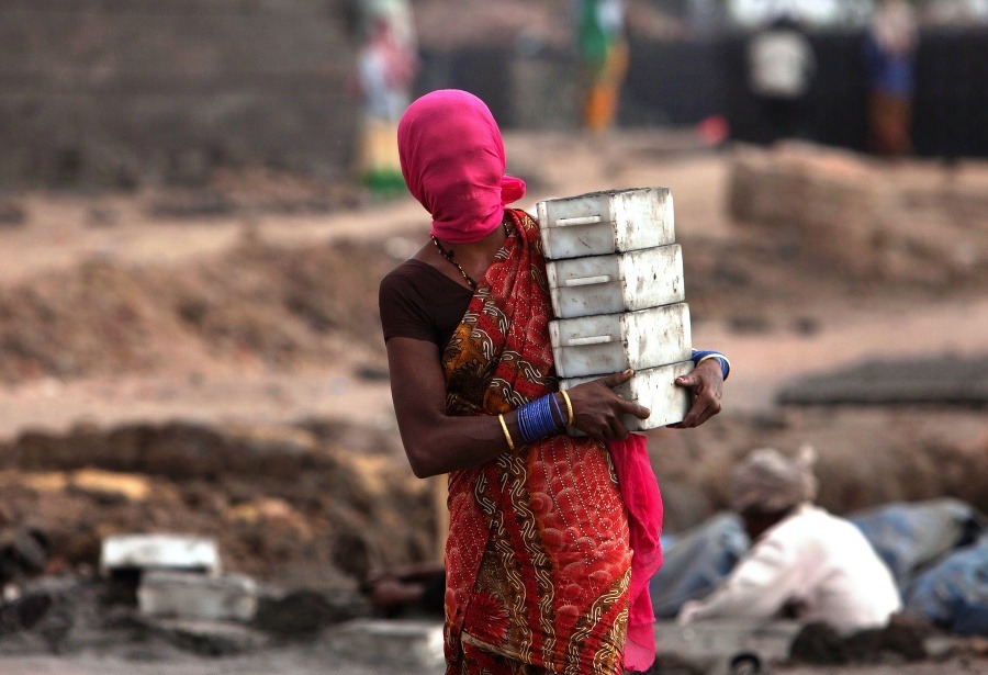 Indická žena so zakrytou tvárou proti prachu pracuje v tehelni v Hajdarabáde.
