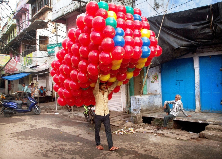 Indický predavač farebných balónikov si nesie tovar z veľkoobchodu v Allahabáde.