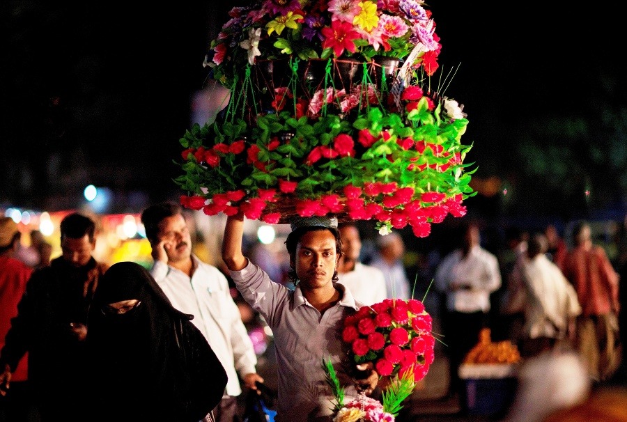 Na snímke indický pouličný predavač kvetov nesie tovar na hlave večer v Hajdarabáde.