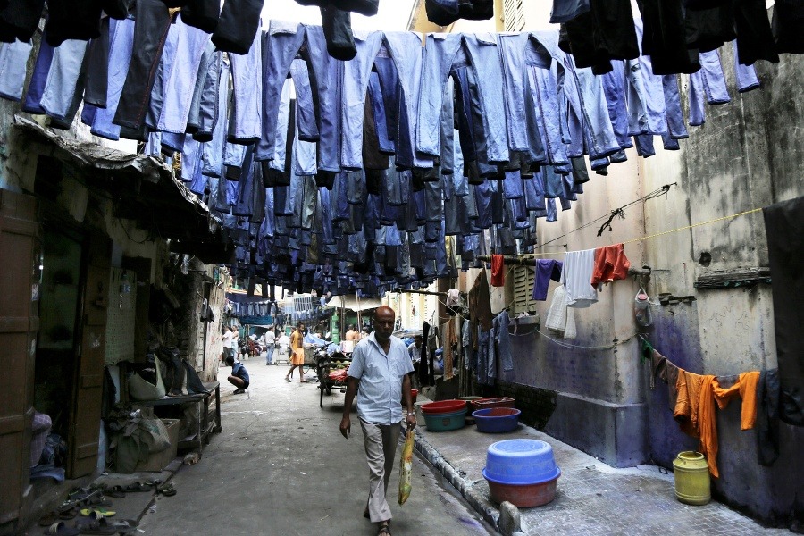 Na snímke sušiace sa oprané džínsy visia cez ulicu na trhu s textilom v indickej Kalkate.