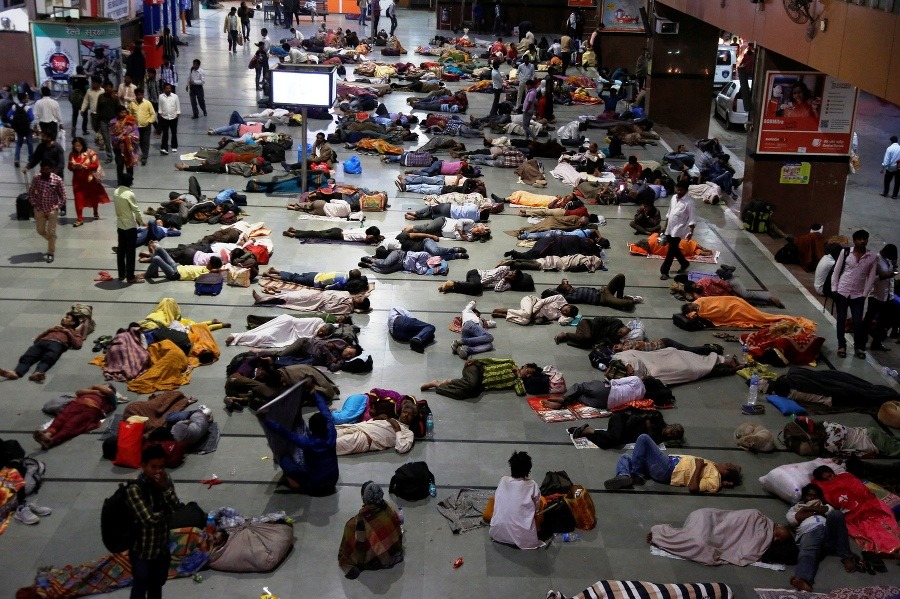 Cestujúci odpočívajú počas čakania na vlak na železničnej stanici v indickom Ahmadabáde.