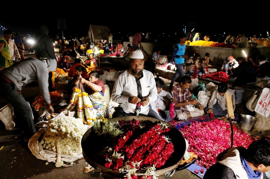 Indický predavač kvetov vytvára girlandy na trhovisku v indickom Ahmadabáde.