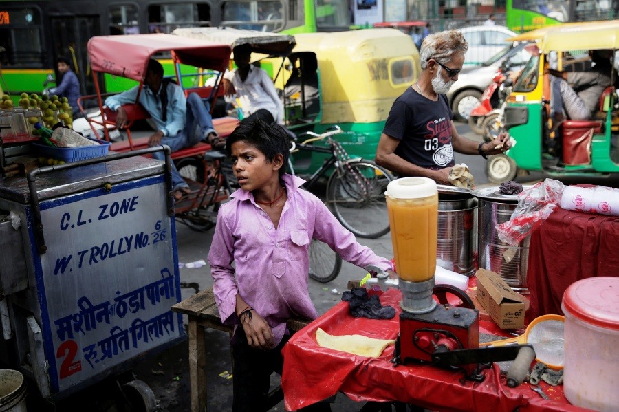 Mladý indický pouličný predavač občerstvenia ponúka ovocný džús a mliečne kokteily v indickom Naí Dillí.