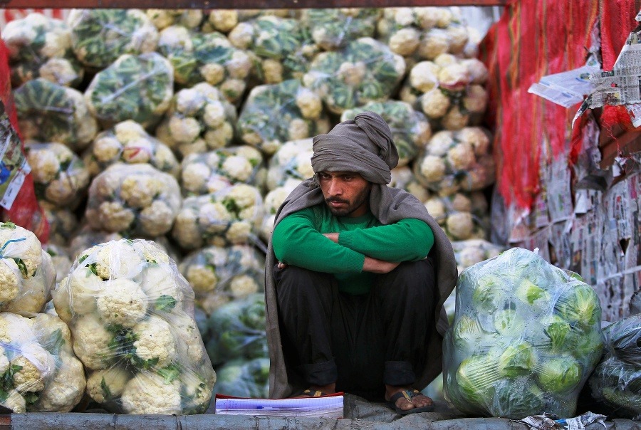Indický roľník, ktorý predáva karfiol,  čaká na zákazníkov na trhu so zeleninou na okraji Džammú v Indii.
