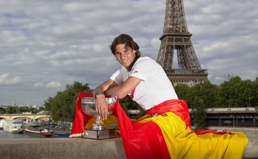 Rafael Nadal pózuje s víťaznou trofejou z Rolland Garros a španielskou zástavou.