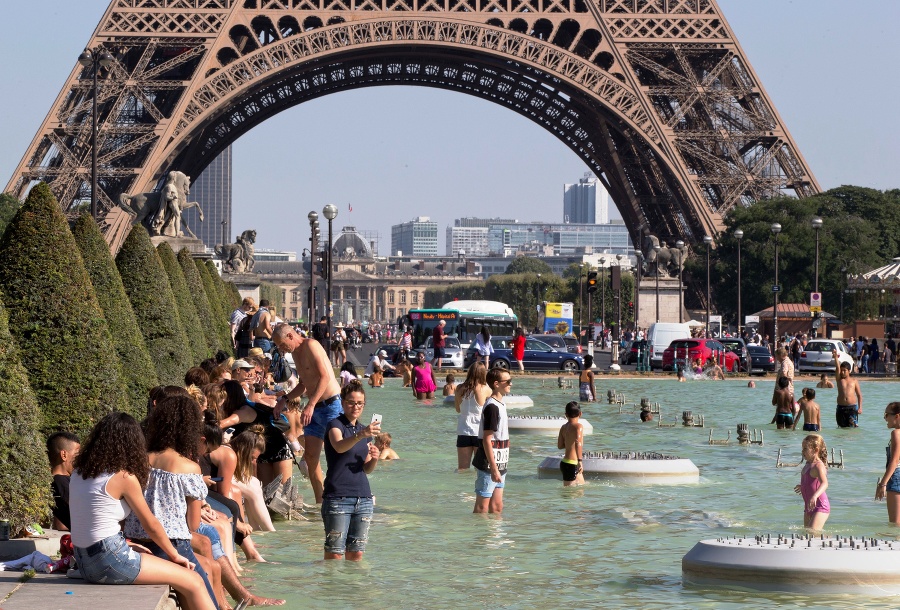 Ľudia si užívajú pri fontáne na parížskom Trocadére počas horúceho letného dňa.