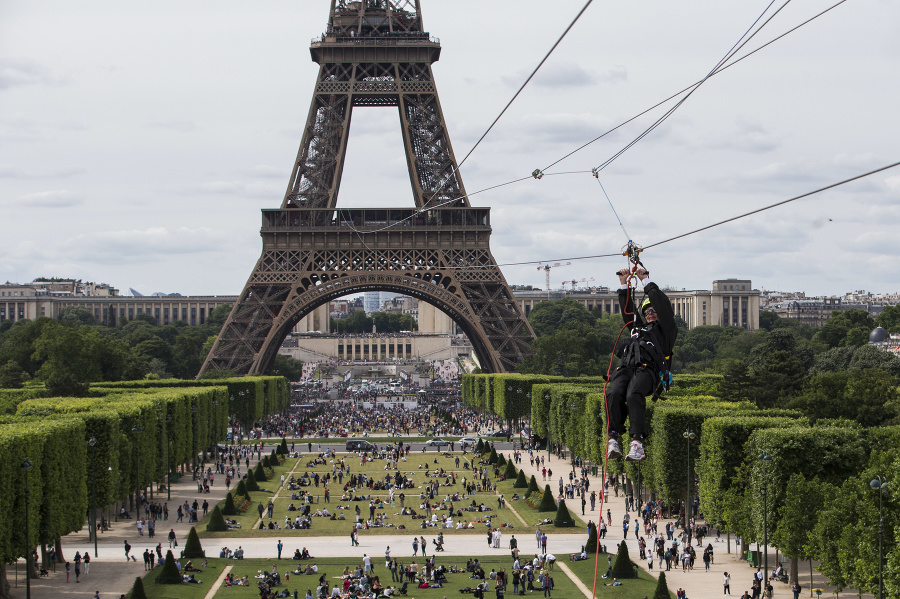 Na snímke muž sa počas špeciálneho podujatia spúšťa na lane z druhého poschodia Eiffelovej veže.