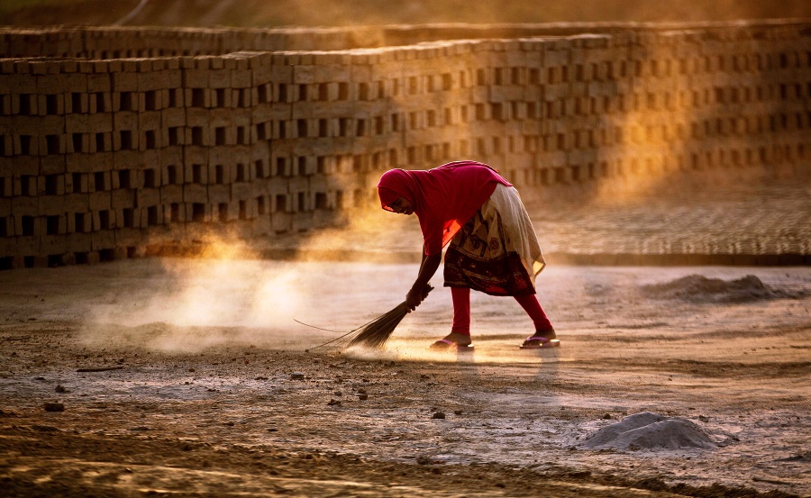 Žena zametá zem v tehelni.