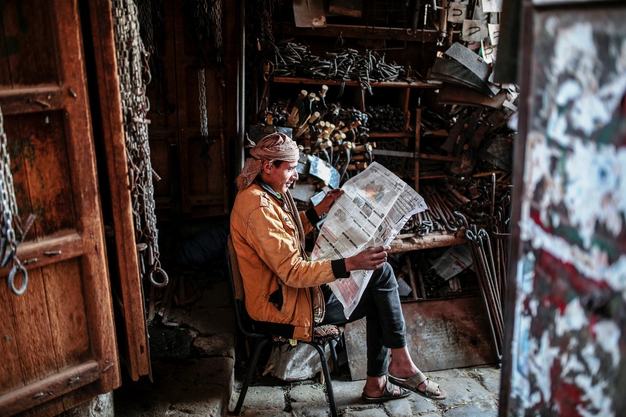 Predavač číta noviny vo svojom stánku na trhu v hlavnom meste,