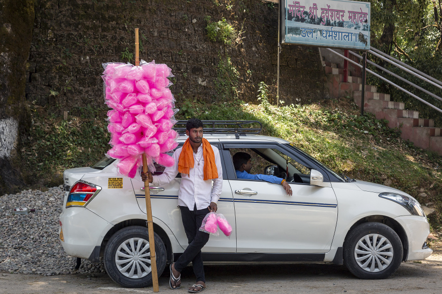 Pouličný predavač cukrovej vaty čaká na zákazníkov opierajúc sa o taxík v Dharmsale.