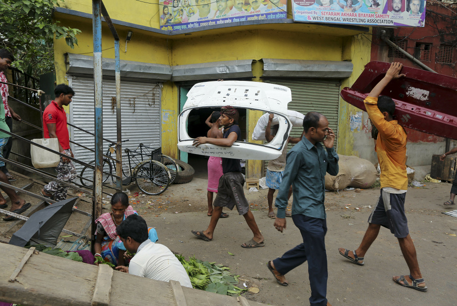 Muži nesú časti karosérie automobilov na šrot v Kalkate.