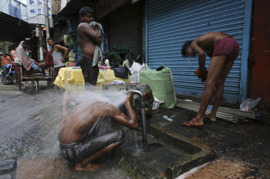 Muži sa umývajú pri verejnom vodovode na okraji cesty skoro ráno v Kalkate.