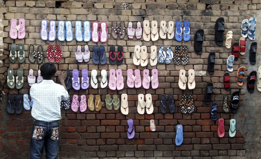 Pouličný predavač ponúka na predaj sandále na okraji indického mesta Džammú.