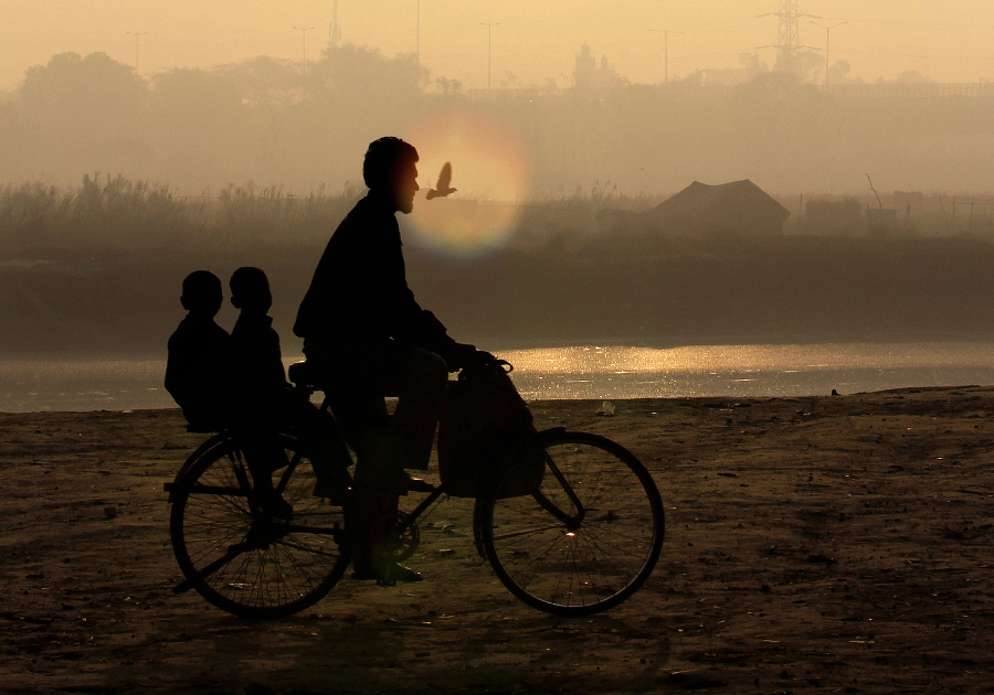 Otec na bicykli vezie svoje deti do školy v Naí Dillí.