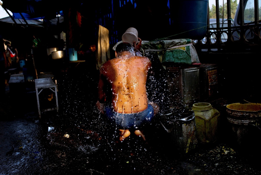 Muž, ktorý žije na ulici, počas ranného kúpeľa v starej časti metropoly Naí Dillí