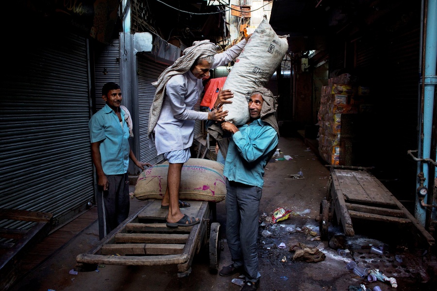 Robotníci vykladajú tovar z vozíka v starej časti metropoly Naí Dillí.
