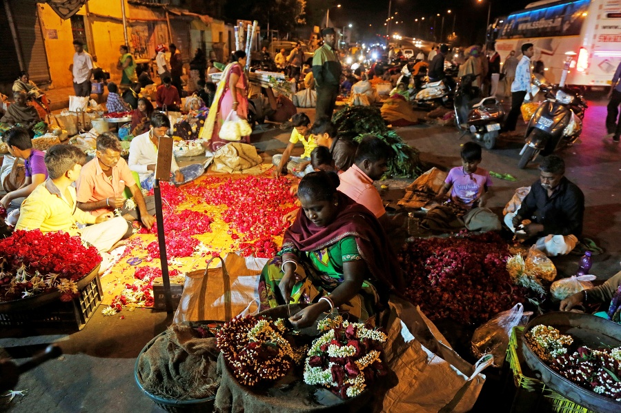 Indickí predavači kvetov vytvárajú girlandy na trhovisku v indickom Ahmadabáde.
