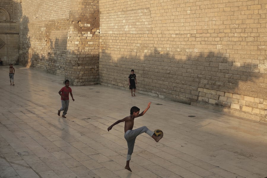 Chlapci hrajú futbal  pred mešitou.