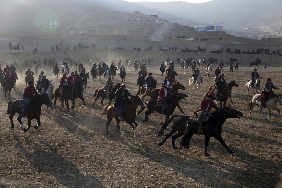 Jazdci na koňoh bojujú o kozu počas tradičného zápolenia v buzkaši v Kábule.
