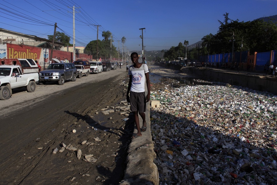 Muž kráča pri brehu totálne znečistenej rieky v haitskej metropole Port-au-Prince.