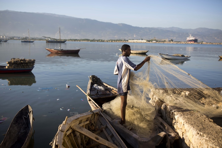 Rybár pripravuje sieť na lov na okraji slumu Cite Soleil v Port-au-Prince.