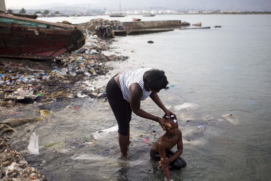 Žena kúpe svoju dcéru v prístave Port Cite Soleil.