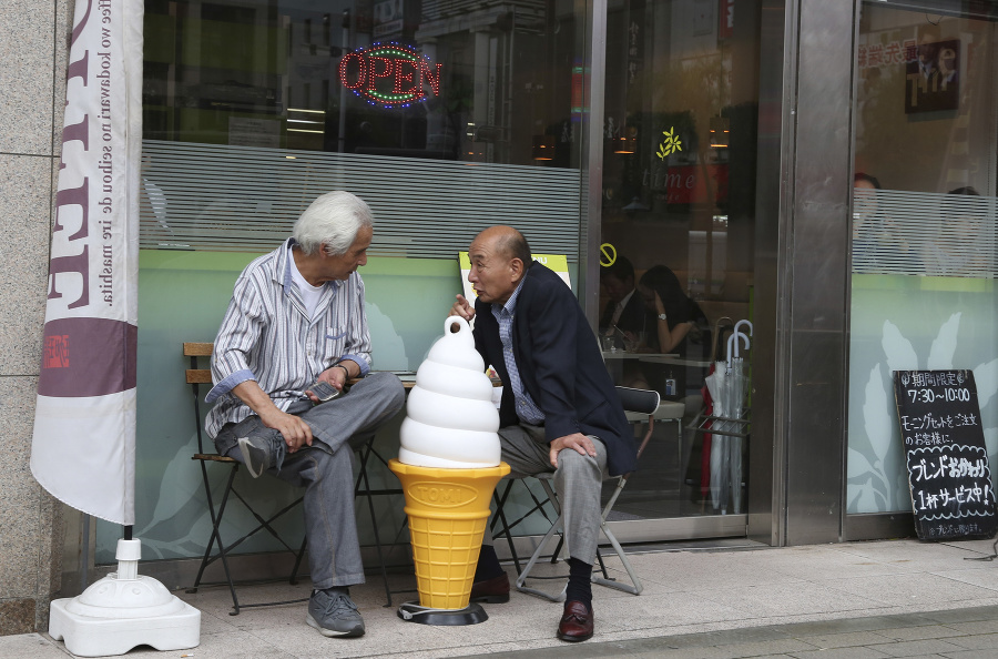 Dvaja muži sa rozprávajú pred kaviarňou v Tokiu.