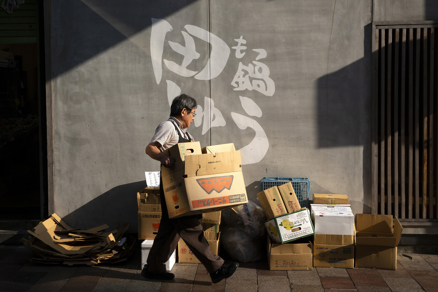 Muž nesie krabice pred obchodom s ovocím v meste Kuamoto.