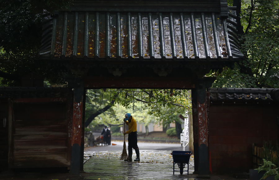 Muž zametá pred bránou do svätyne Tošogu šrine v parku Ueno v Tokiu.